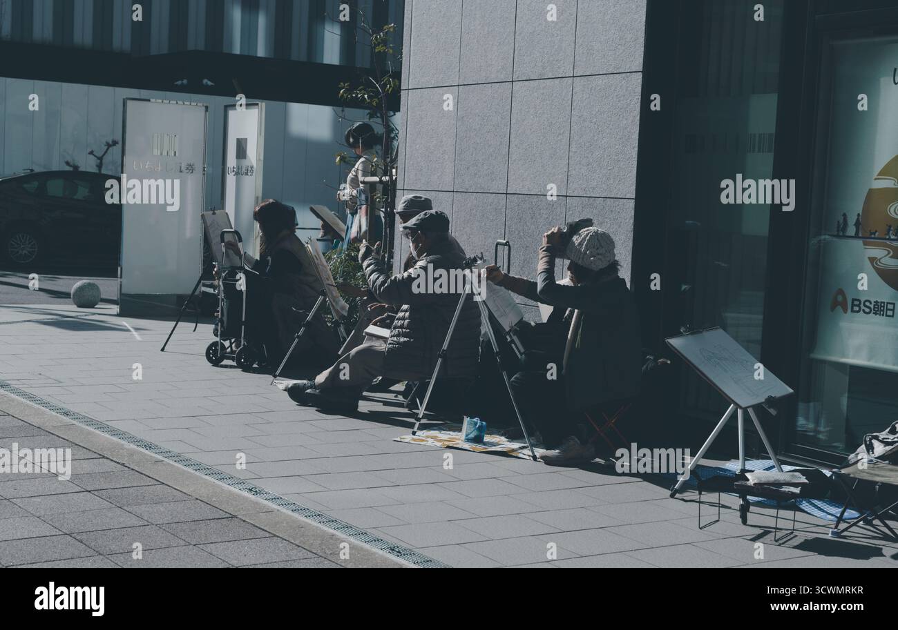 Gli artisti si siedono e lavorano in fila lungo un edificio di Osaka Foto Stock