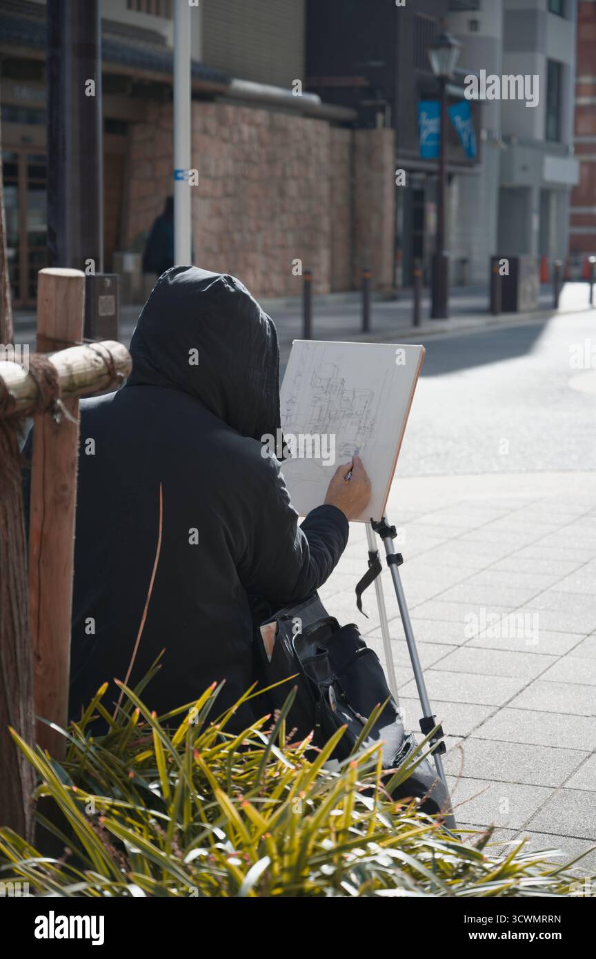 L'artista con cappuccio disegna il paesaggio urbano in una mattinata tranquilla nel Chuo Ward di Osaka Foto Stock