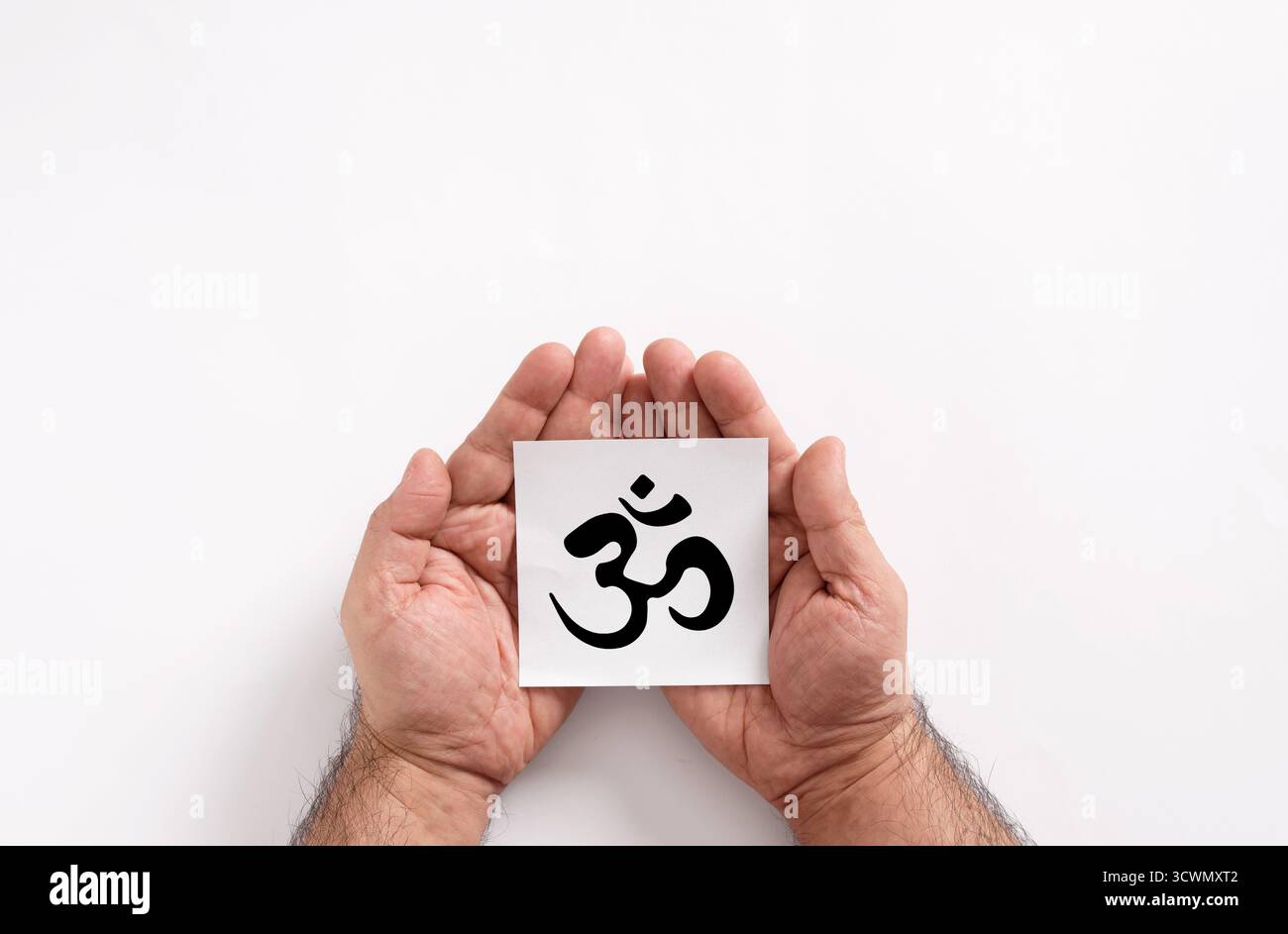 Apri le mani tenendo in mano un cartellino bianco con stampato il simbolo om, che rappresenta l'induismo e la meditazione Foto Stock