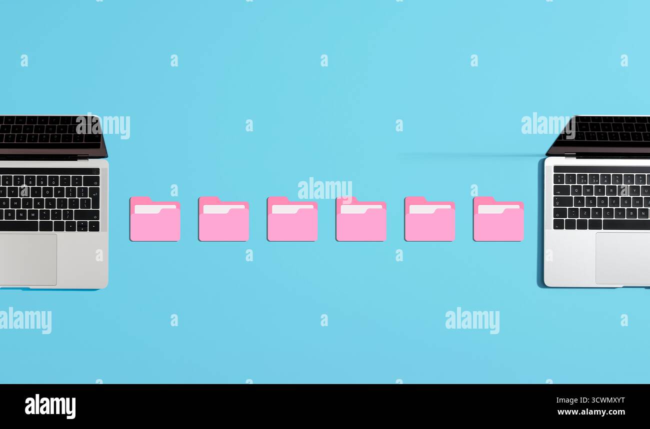 Cartelle digitali rosa che trasferiscono file tra due laptop su uno sfondo blu brillante, che rappresenta la condivisione e lo scambio di dati Foto Stock