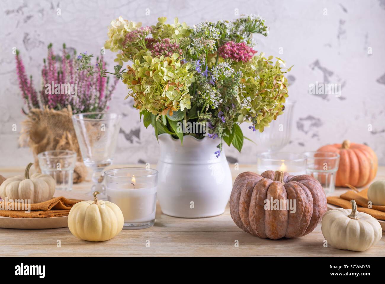 Bellissimo bouquet di fiori autunnali in zucca su un tavolo da pranzo festivo Foto Stock