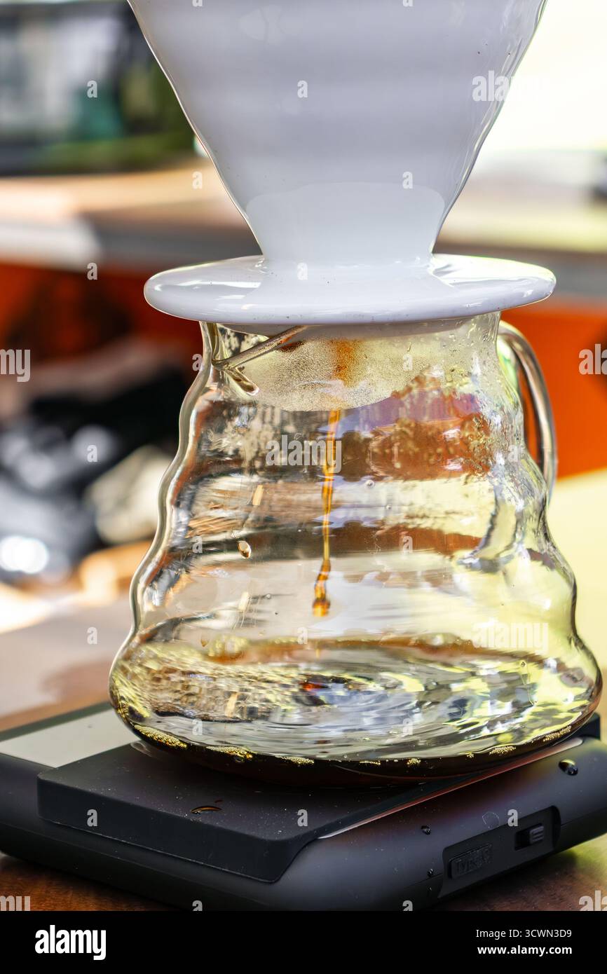 Un barista prepara il caffè utilizzando il metodo Pour-over versando acqua in un imbuto con filtro e chicchi di caffè durante una festa del caffè. Foto Stock
