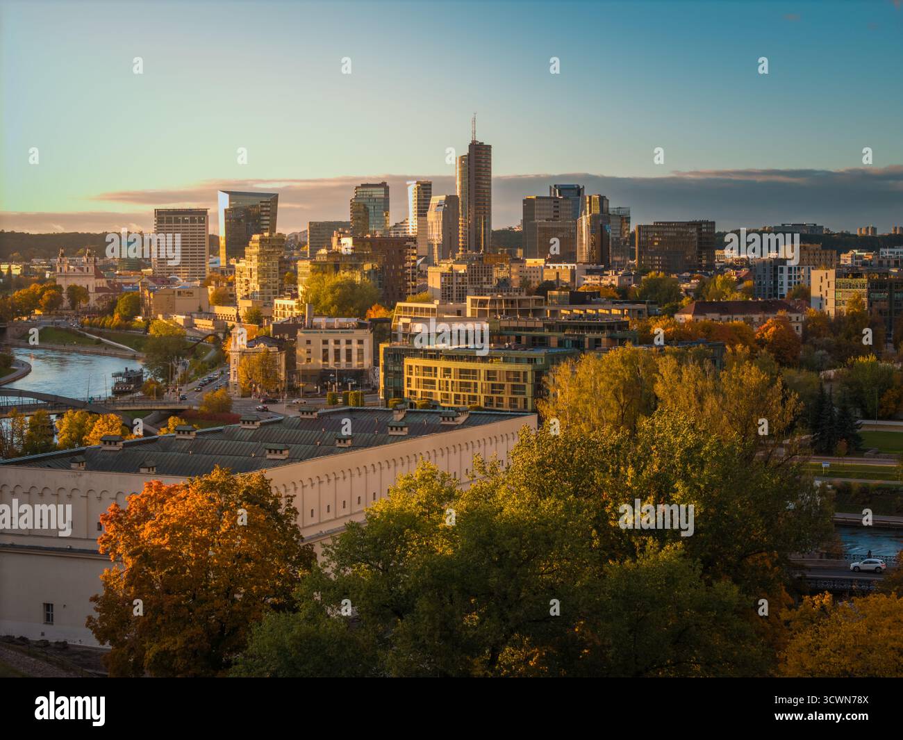 Vista aerea dei grattacieli che perforano lo skyline oltre gli alberi autunnali e il tortuoso fiume Neris, Vilnius, Lituania. Foto Stock