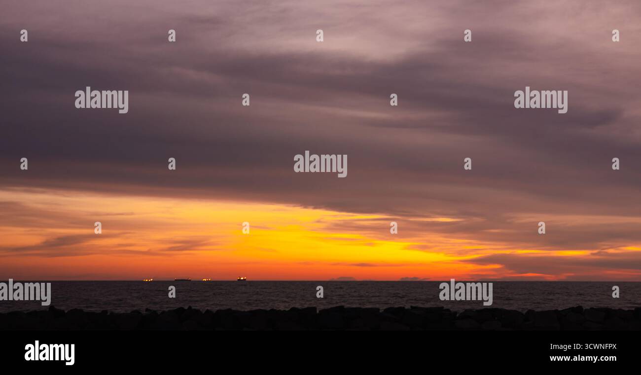 Splendido tramonto sull'oceano con cielo colorato e orizzonte marino calmo sotto la calda luce serale, perfetto per viaggi, natura e design dello sfondo. Foto Stock