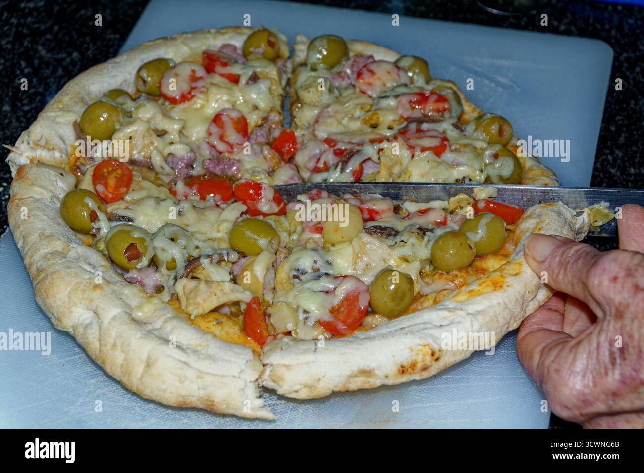 Pizza - base margherita con extra tagliati in quattro per servire. Foto Stock