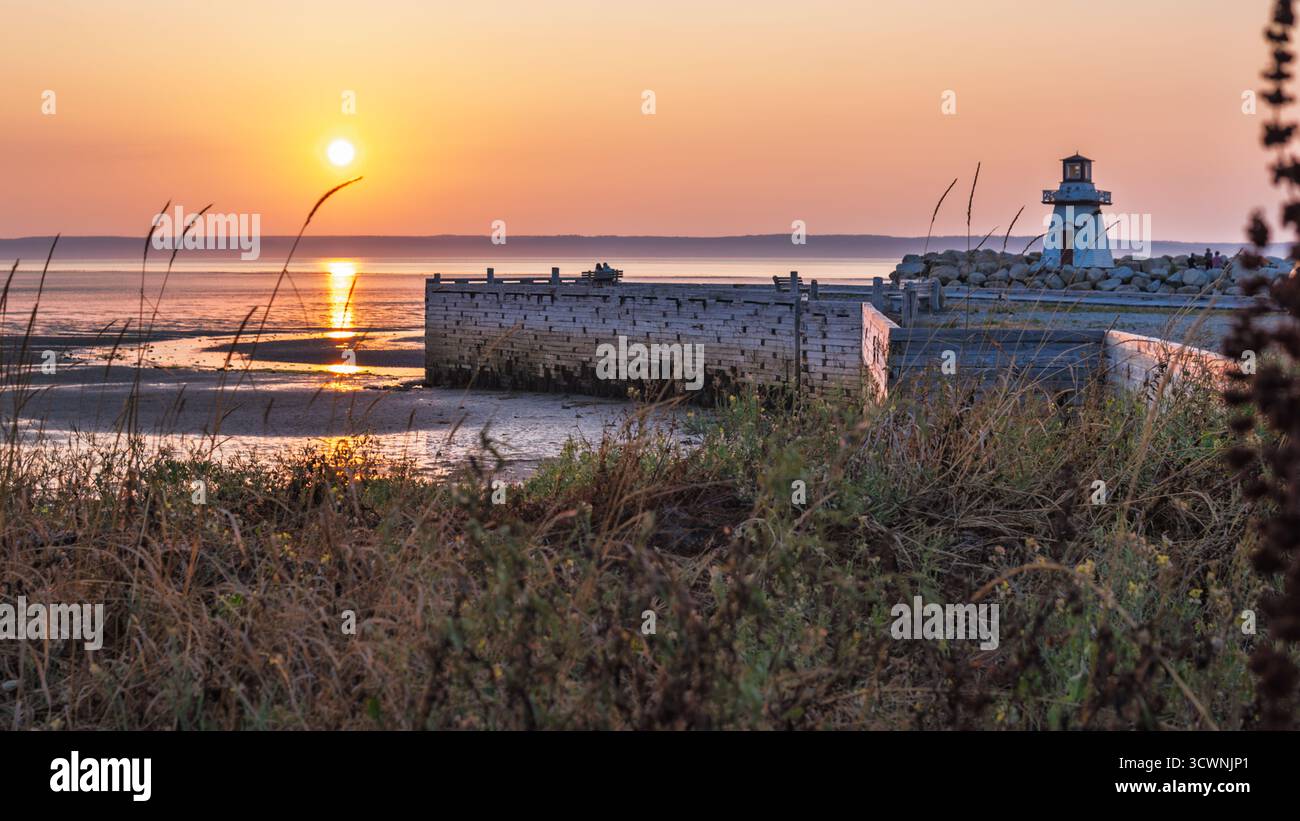 Coppia seduta accanto al faro guardando il tramonto con la bassa marea Foto Stock
