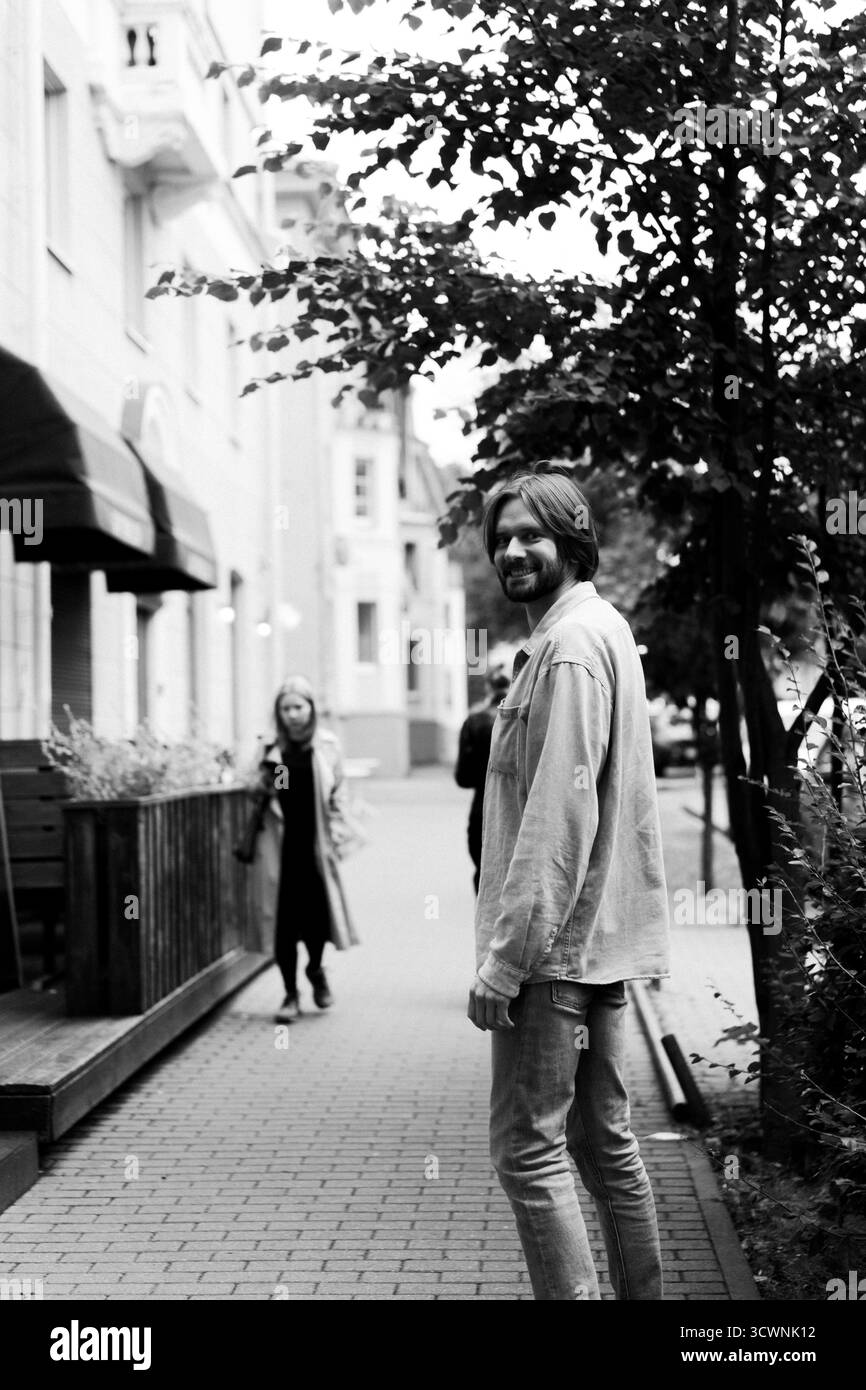 Uomo barbuto felice sorridente sul marciapiede urbano, ritratto in bianco e nero Foto Stock