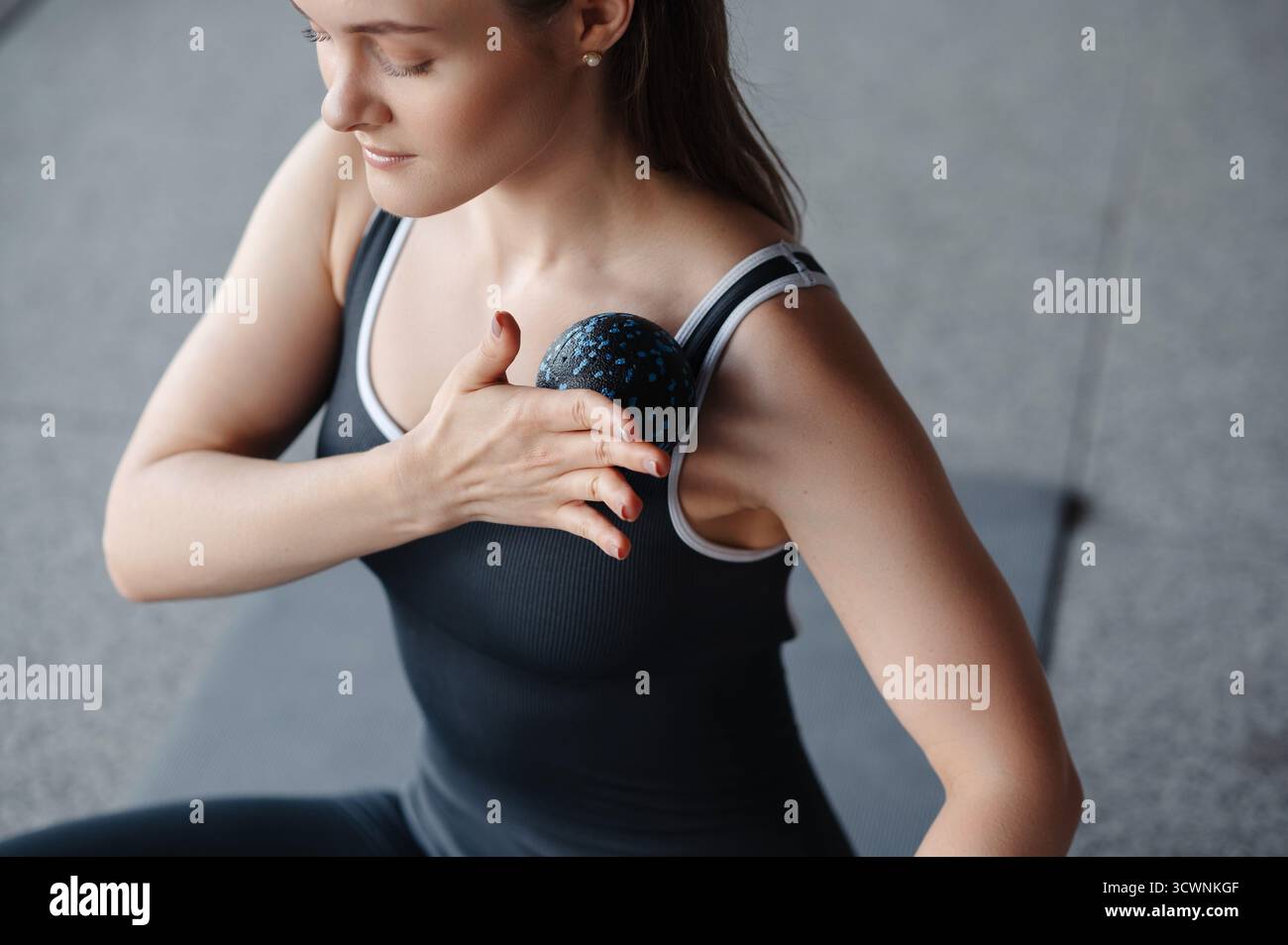 Donna che usa la palla da massaggio per il sollievo alle spalle Foto Stock