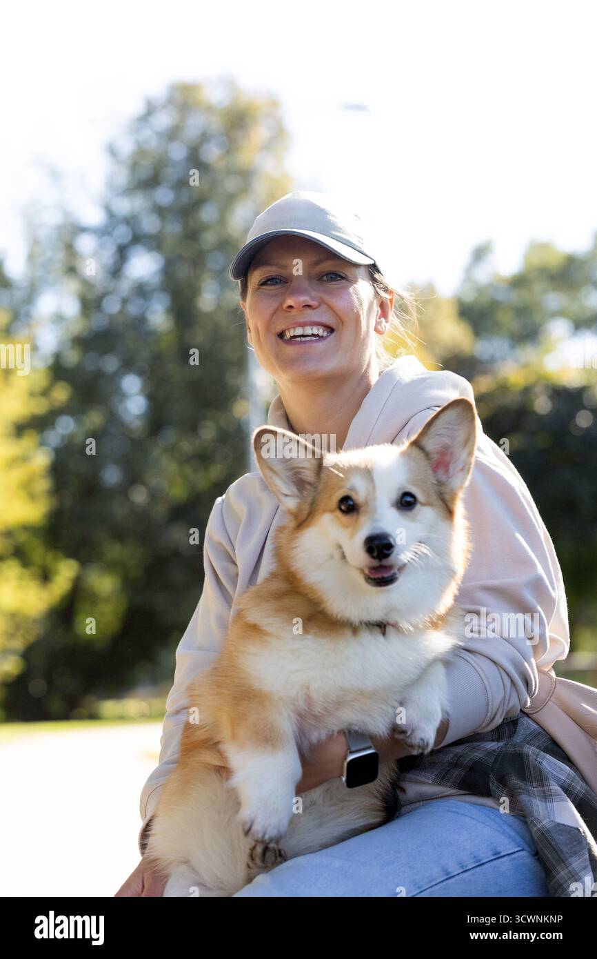 padrona di cane sulla panchina con cane corgi, giornata d'autunno soleggiata Foto Stock