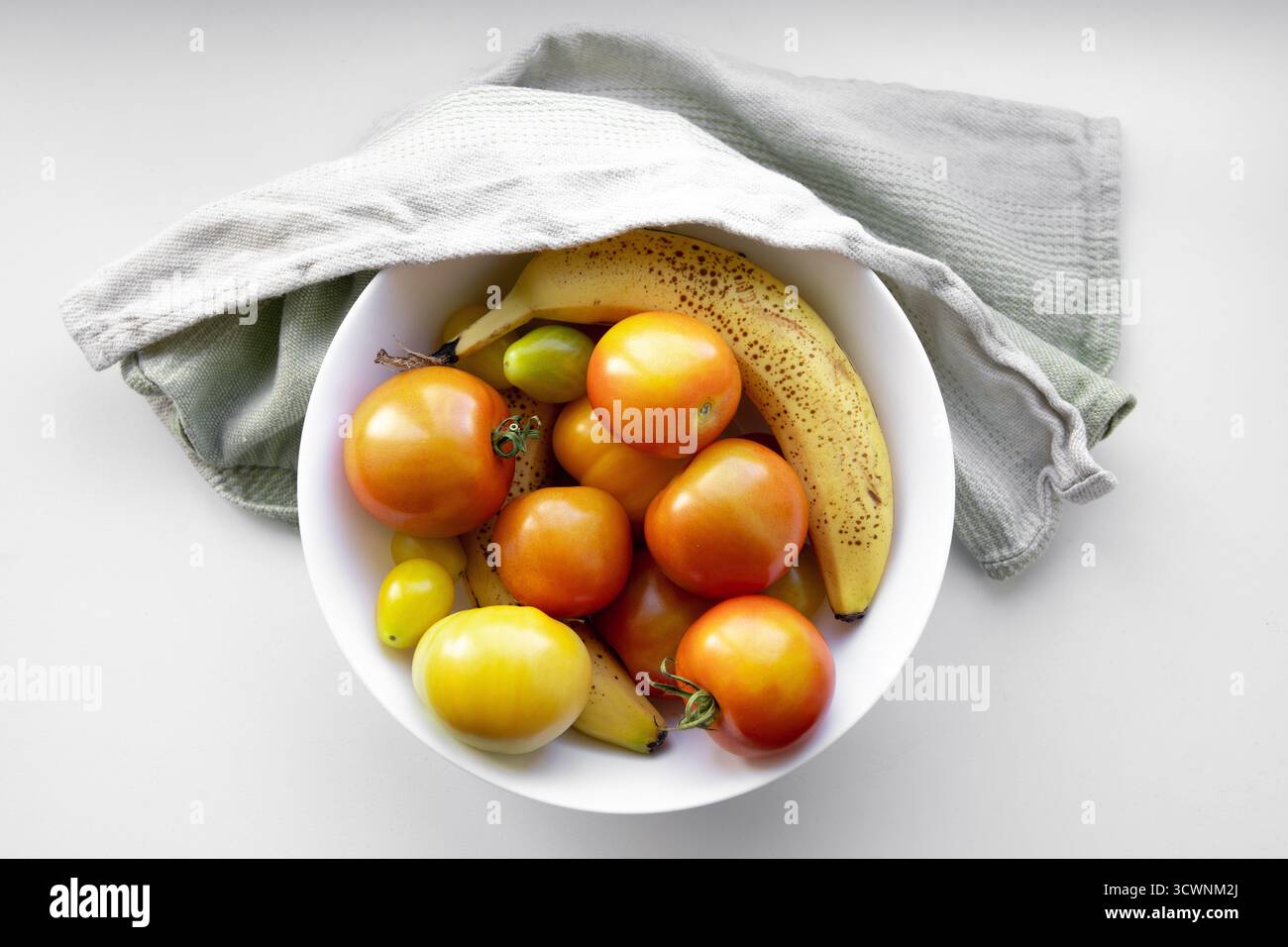 La maturazione di pomodori verdi crudi con banane è efficace perché il gas etilenico della banana accelera il processo. Foto Stock