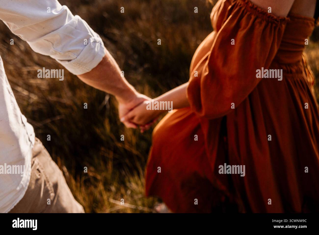 Primo piano di una coppia che tiene le mani in una calda luce dorata all'aperto Foto Stock