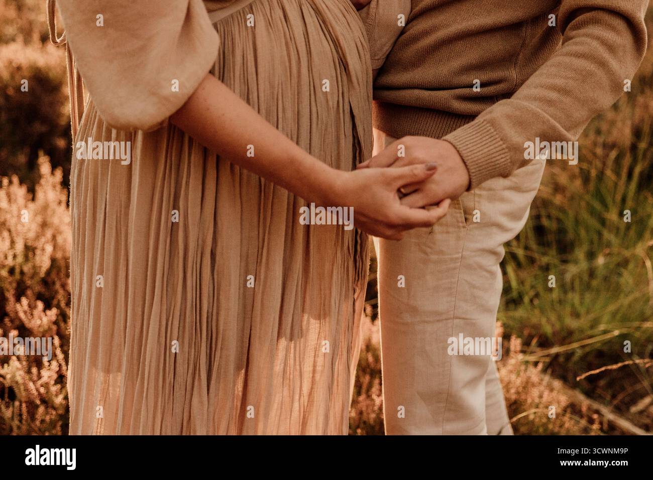 Primo piano di una coppia che tiene le mani in una calda luce dorata all'aperto Foto Stock