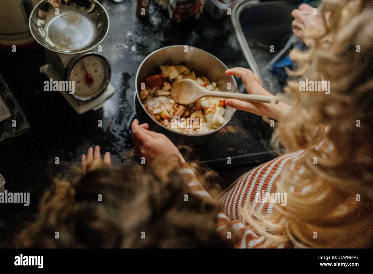 I bambini mescolano gli ingredienti dei dessert di mele in cucina Foto Stock