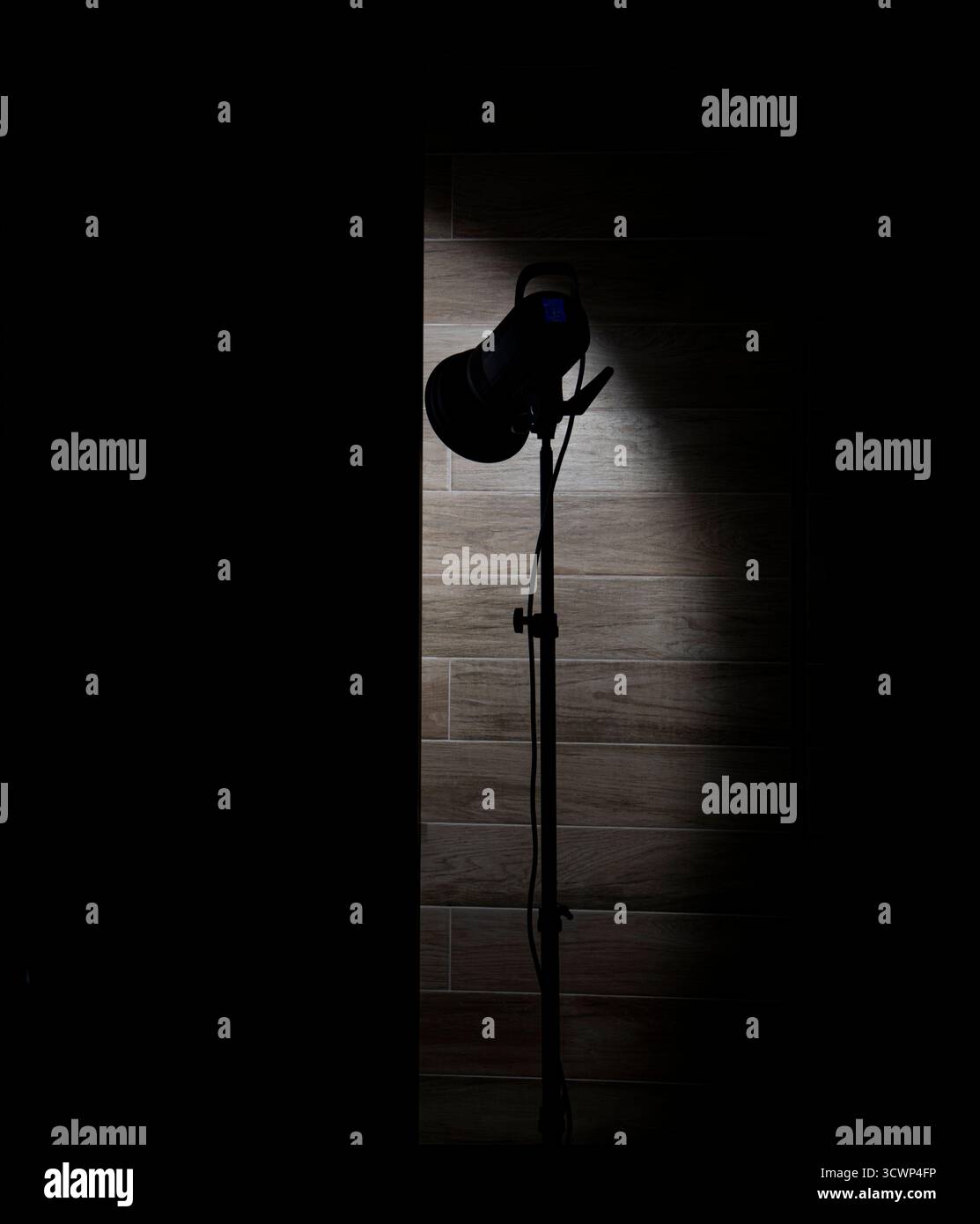 Faretto studio che illumina una parete di legno in una stanza buia. Foto Stock