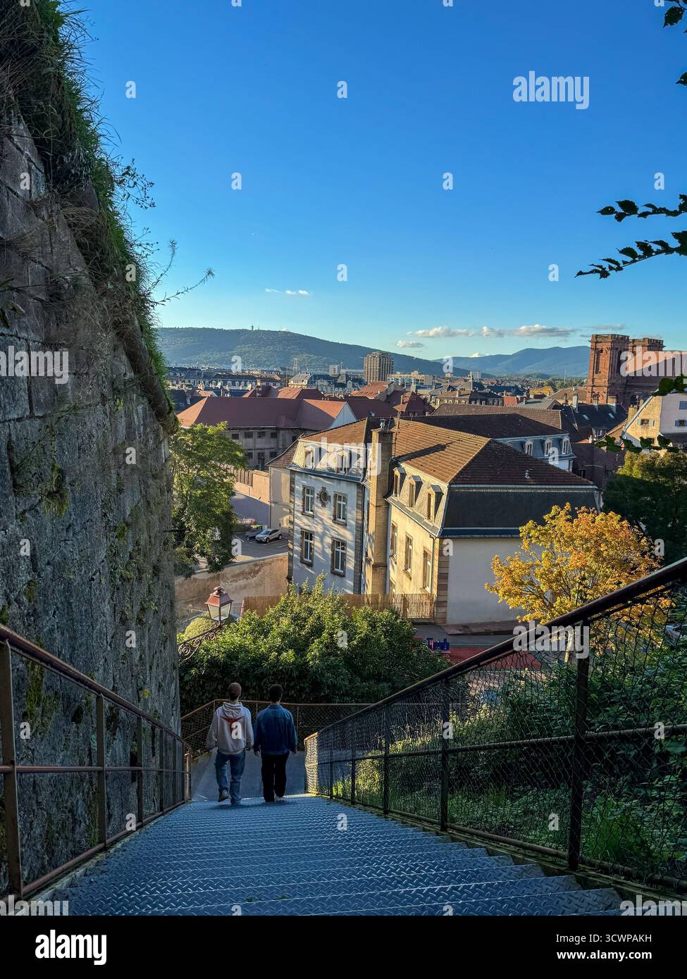 Vista panoramica dall'Allée de l'Option Francaise a Belfort, Francia, dalla scalinata di metallo lungo i bastioni della Cittadella, con due persone che scendono - Immagine stock catturata con smartphone