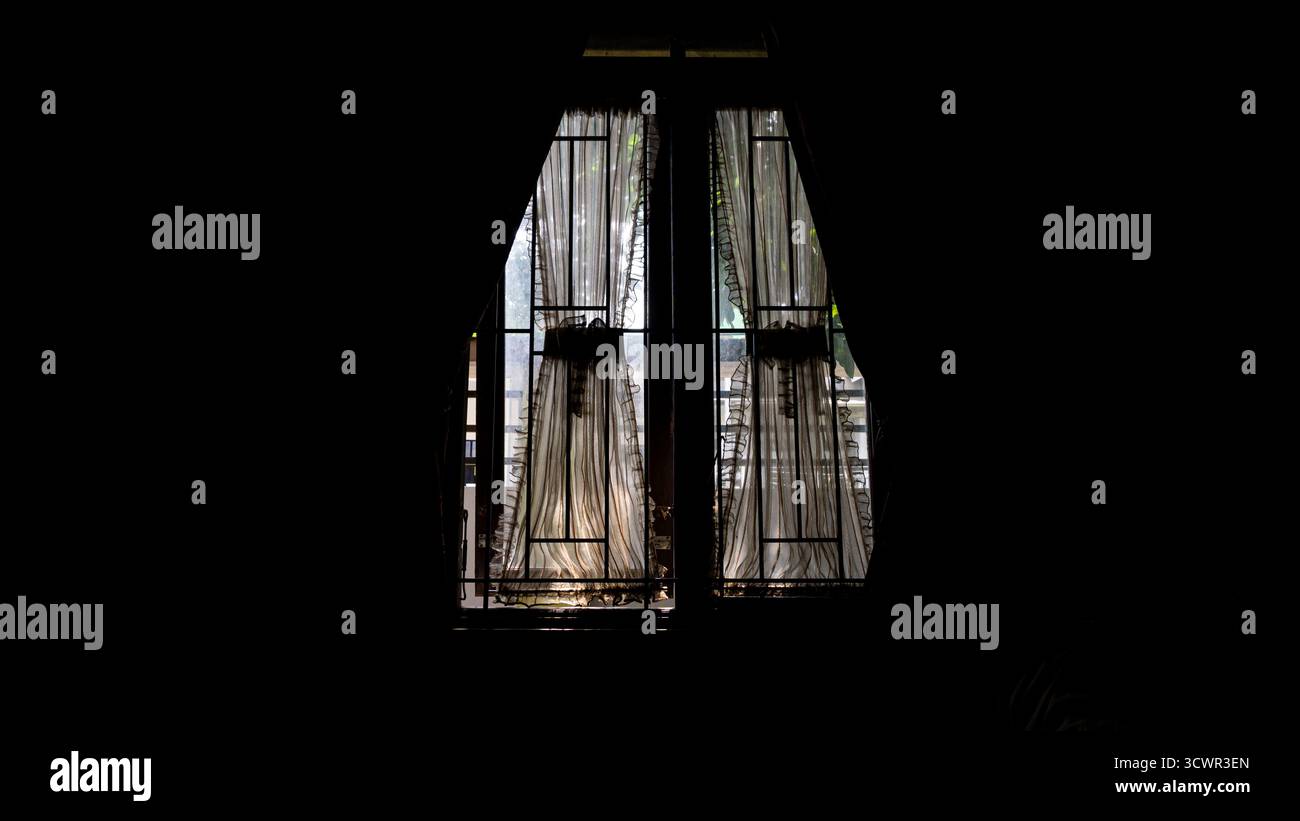 La finestra vista dall'interno della casa, sembra nera sul lato e luminosa fuori dalla casa Foto Stock