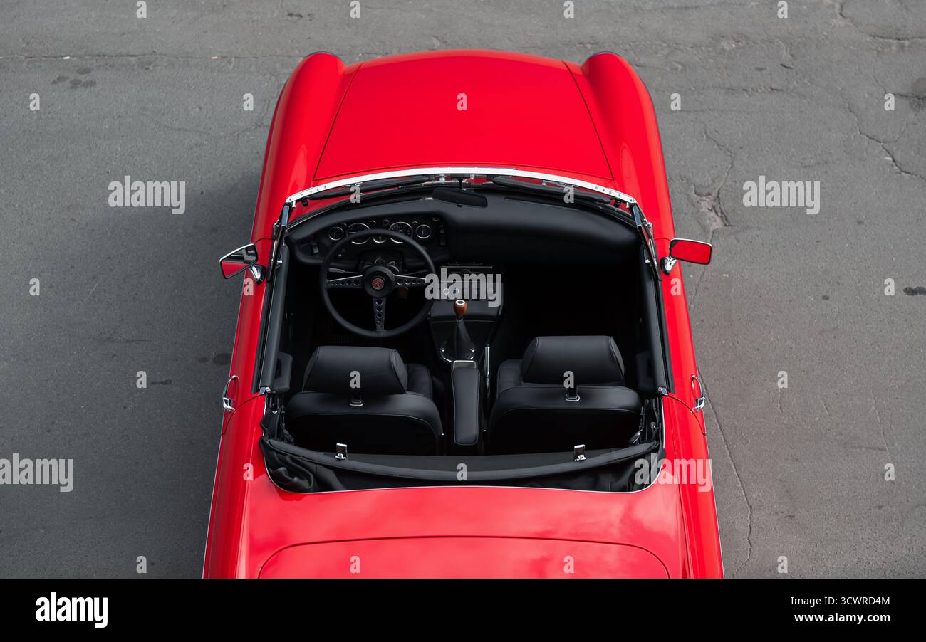 Vecchia cabriolet rossa - vista dall'alto della cabina di pilotaggio. Roadster a due posti MG MGB anni '1960 con interni in pelle nera. Foto Stock