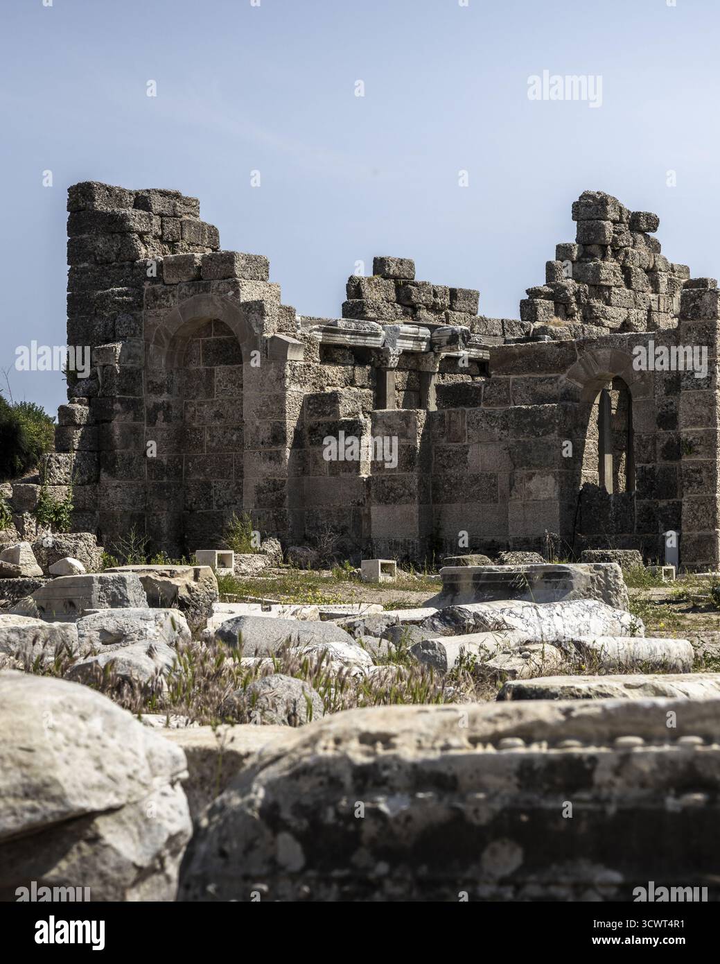 La vista delle antiche rovine soleggiate si erge come testimoni silenziosi del tempo, un netto contrasto con il cielo azzurro cristallino, racconti sussurranti di epoche dimenticate, Side, Antalya, Turchia. Foto Stock