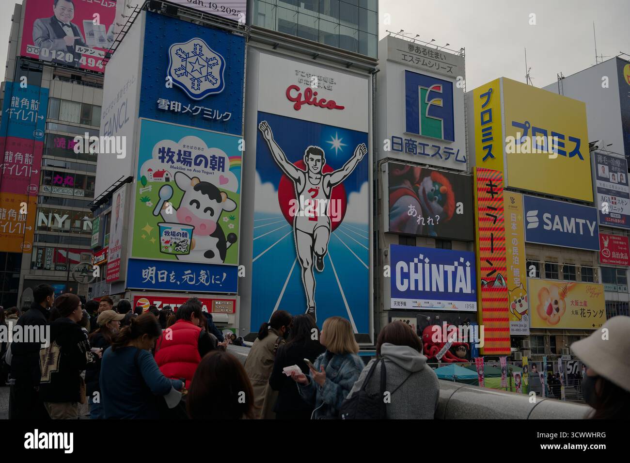 La folla si riunisce a Dotonbori, dove l'iconico Glico Running Man si erge sullo sfondo Foto Stock