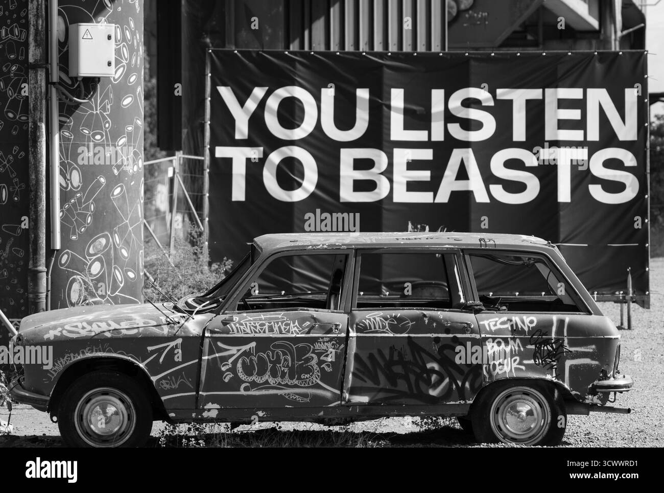 Graffiti ha coperto l'auto abbandonata in ambiente urbano con Street Art e Billboard Text – Contemporary City Scene Foto Stock