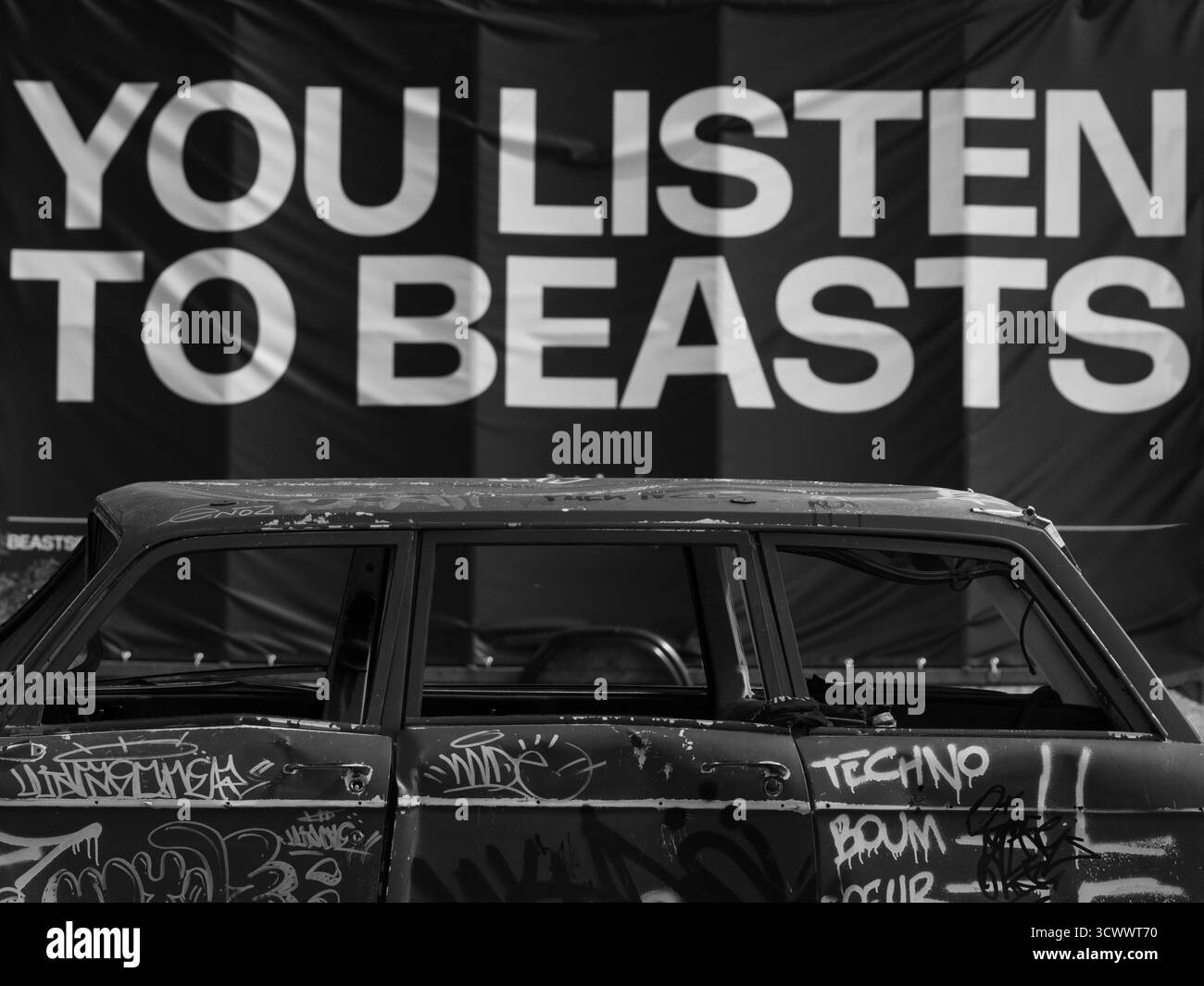 Graffiti ha coperto l'auto abbandonata in ambiente urbano con Street Art e Billboard Text – Contemporary City Scene Foto Stock