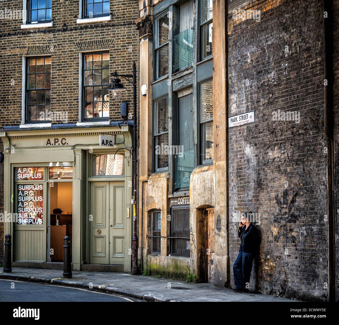 Un vicolo urbano, vicino al Borough Market di Londra, fiancheggiato da vecchi edifici in mattoni e da una figura solitaria che parla al suo cellulare. Foto Stock