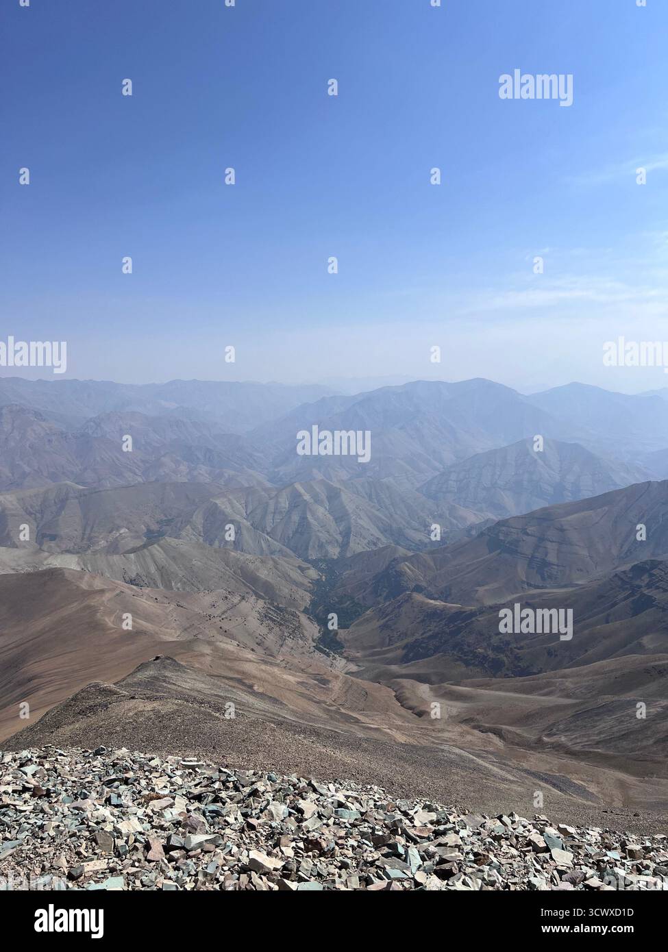 Vista dal picco Tochal a Teheran con terreno roccioso e montagne stratificate sotto un cielo azzurro. Foto Stock