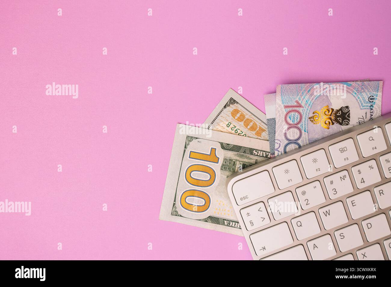 Tastiera per computer con dollari USA e Kazakistan su sfondo rosa pastello Foto Stock