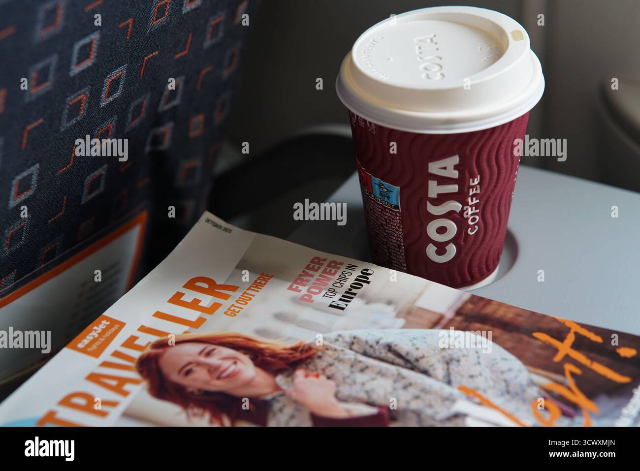 Tazza di caffè Costa e rivista di bordo easyJet Traveller su un vassoio durante il volo all'interno della cabina dell'aereo. Monaco, Germania Foto Stock