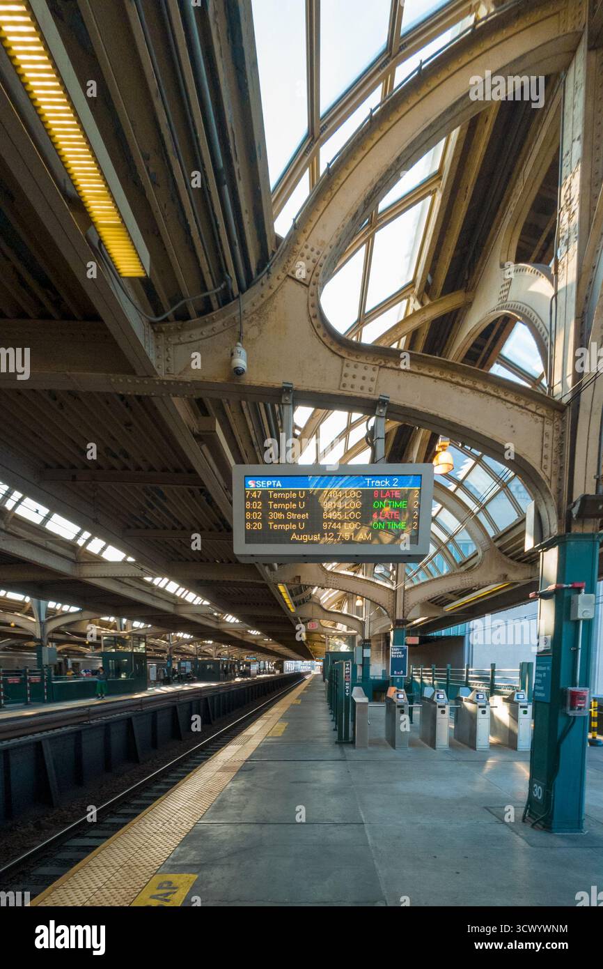 Una stazione Spring Garden con un grande schermo che mostra l'ora e il treno successivo. La stazione è vuota e il cielo è nuvoloso Foto Stock Una stazione Spring Garden con un grande schermo che mostra l'ora e il treno successivo. La stazione è vuota e il cielo è nuvoloso Foto Stock