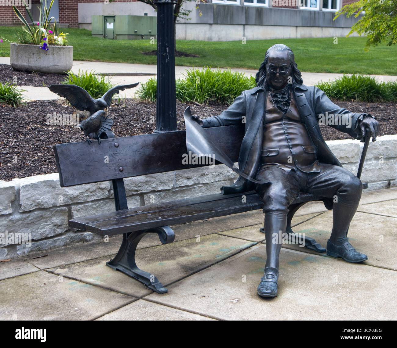 Statua di Ben Franklin seduta su una panchina a Franklin, Indiana, invitando i visitatori a fermarsi, riflettere e godersi il fascino di una piccola città. Foto Stock
