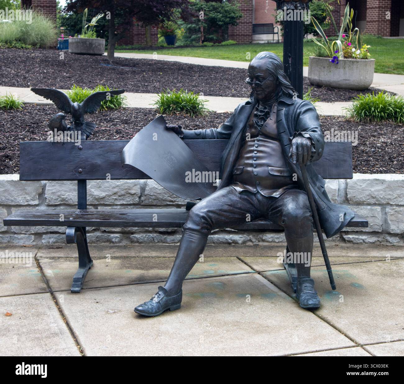 Statua di Ben Franklin seduta su una panchina a Franklin, Indiana, invitando i visitatori a fermarsi, riflettere e godersi il fascino di una piccola città. Foto Stock