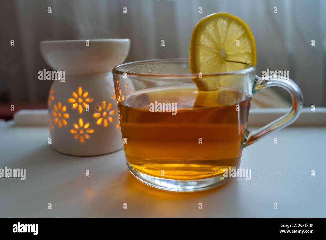 Una tazza di tè nero caldo con limone e una lampada aromatica. Foto Stock