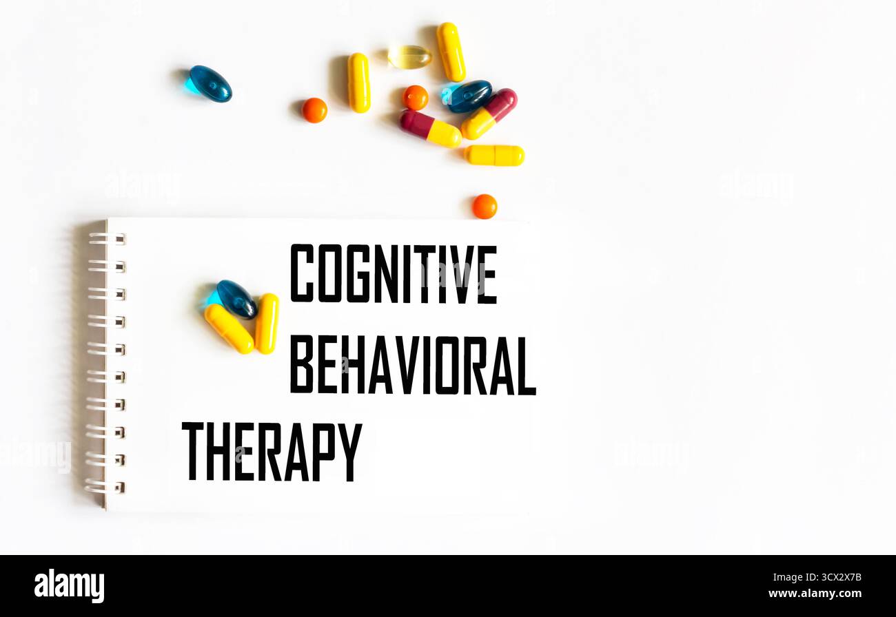 Il testo "TERAPIA COGNITIVA COMPORTAMENTALE" è scritto in un quaderno accanto alle pillole. Concetto medico Foto Stock