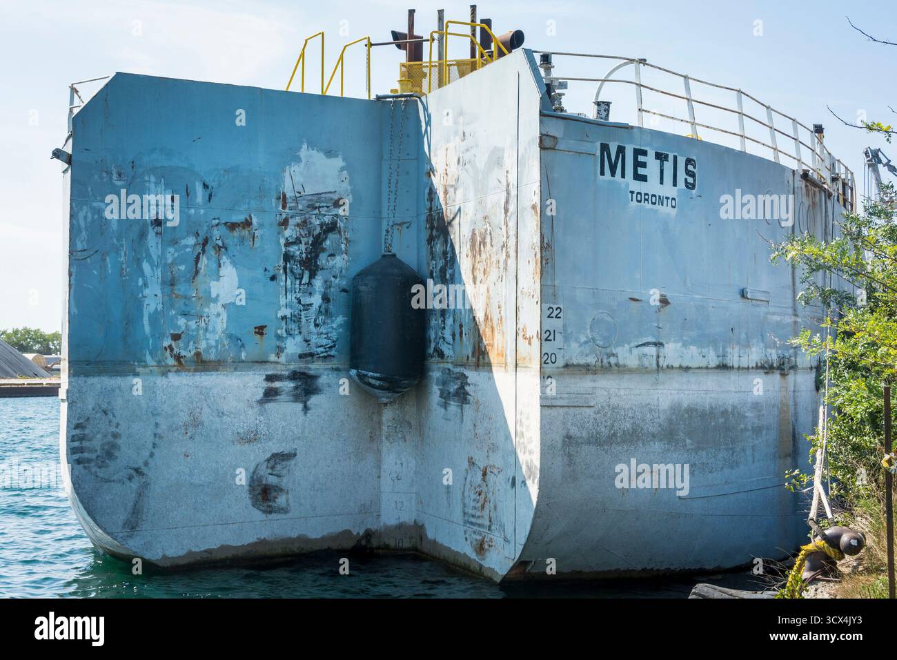 In un canale di spedizione di Toronto, la nave da carico in pensione Metis funge ora da chiatta con una tacca tagliata nella poppa per spingere con un rimorchiatore Foto Stock