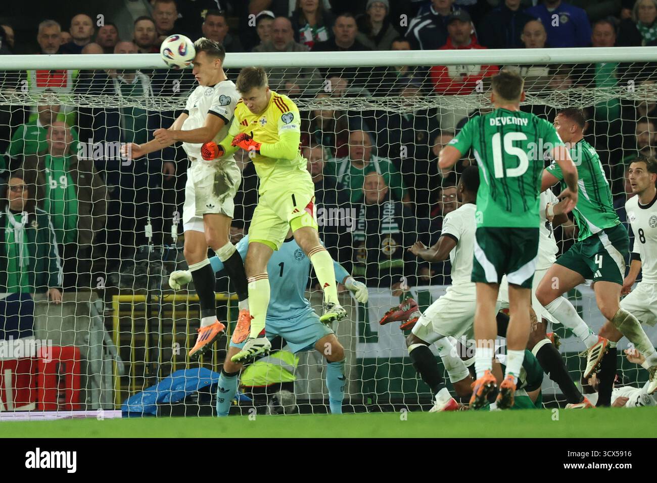 Belfast, Regno Unito. 13 ottobre 2025. Calcio: Qualificazione ai Mondiali Europa, Irlanda del Nord - Germania, fase a gruppi, gruppo A, Matchday 4, Windsor Park, Nico Schlotterbeck (Germania) in un duello di testa con il portiere Bailey Peacock-Farrell (Irlanda del Nord) davanti alla rete tedesca. Credito: Christian Charisius/dpa/Alamy Live News Foto Stock