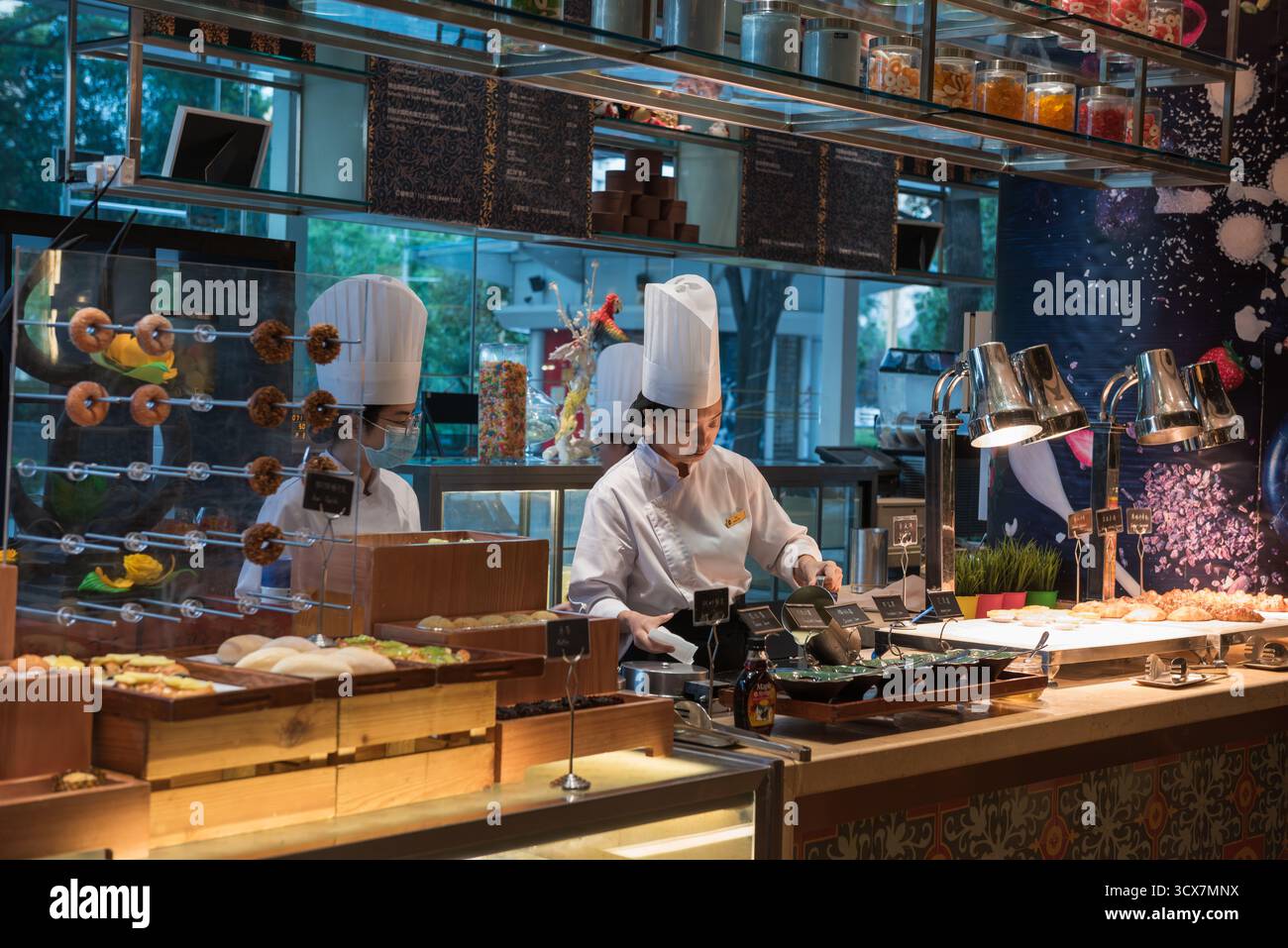 Lo chef lavora alla postazione uova al bar della colazione nell'hotel di lusso Shangri-la, a Chengdu, Cina. Foto Stock