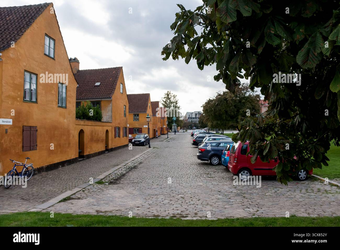 Copenaghen, Danimarca - 28 settembre 2014 - affascinante strada acciottolata con case arancioni e auto parcheggiate. Foto Stock