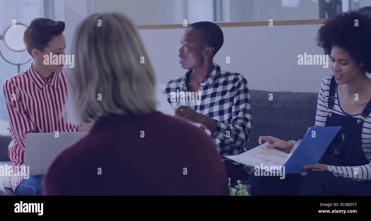 Discutere del progetto quattro colleghi seduti intorno al tavolino da caffè in una sala moderna, con le carte dei computer portatili Foto Stock