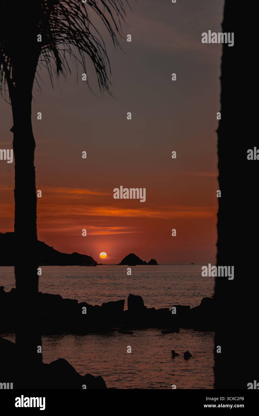 Il sole tramonta tra un'isola sullo sfondo a playa linda, Ixtapa Foto Stock