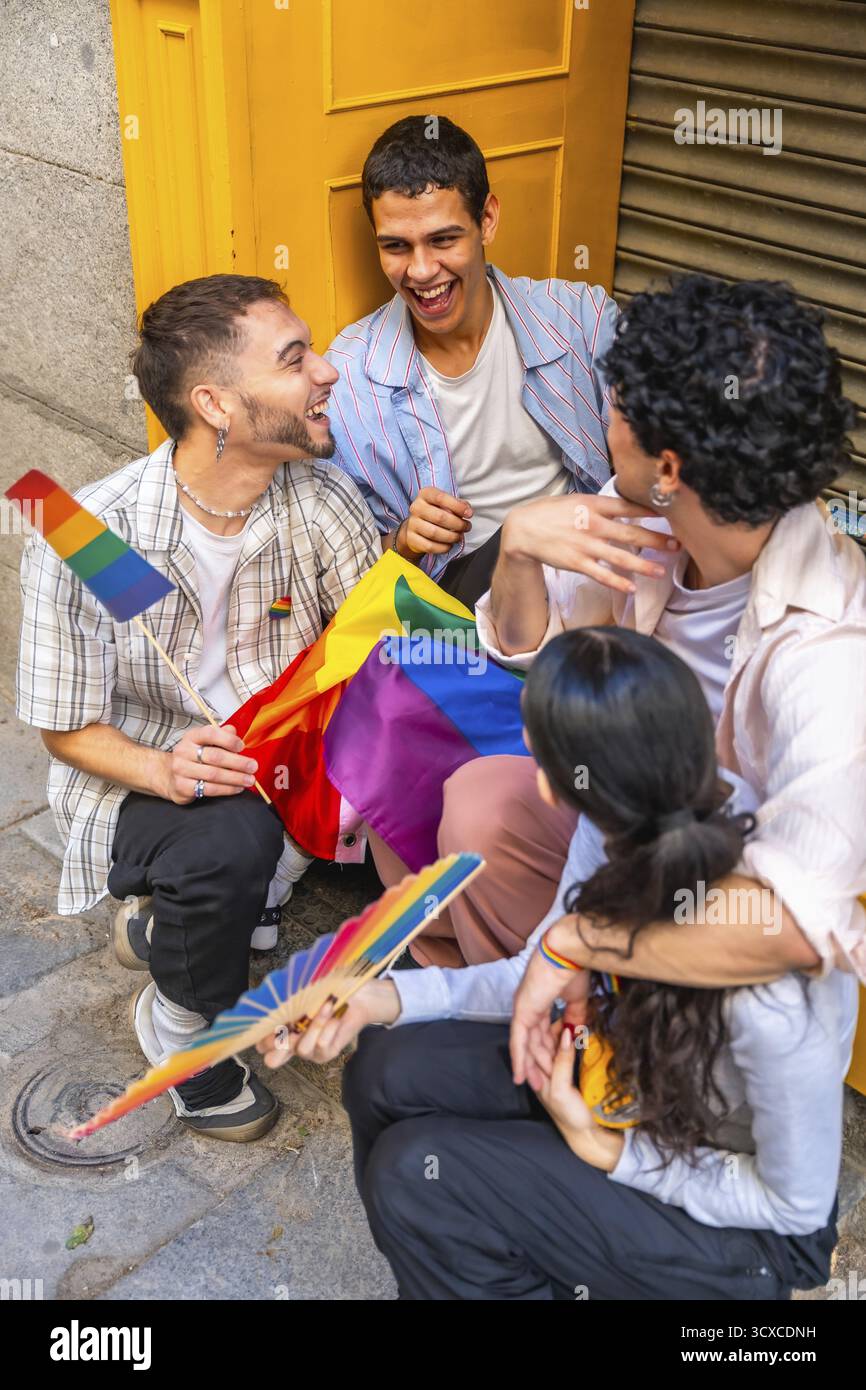Gruppo di giovani amici adulti che si godono un momento di connessione all'aperto, tenendo bandiere arcobaleno ed esprimendo gioia, rappresentando la comunità, EQUAL Foto Stock