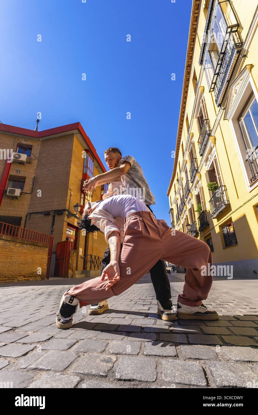Due ballerini esperti impegnati in un'appassionata esibizione contemporanea in una strada acciottolata, esprimendo movimento e connessione in un ambiente urbano Foto Stock