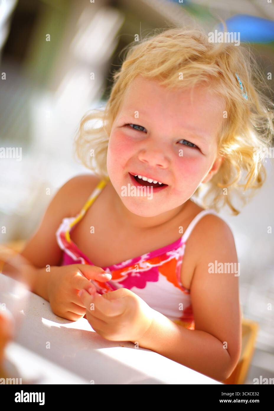 Il bambino biondo sorride in un colorato abito estivo in un ambiente soleggiato Foto Stock