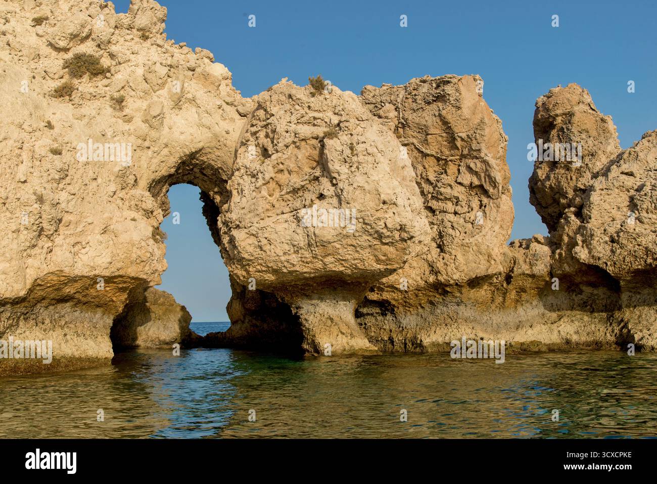 Rocky Coastal Arch con Vista Oceano e tessuti illuminati dal sole Foto Stock
