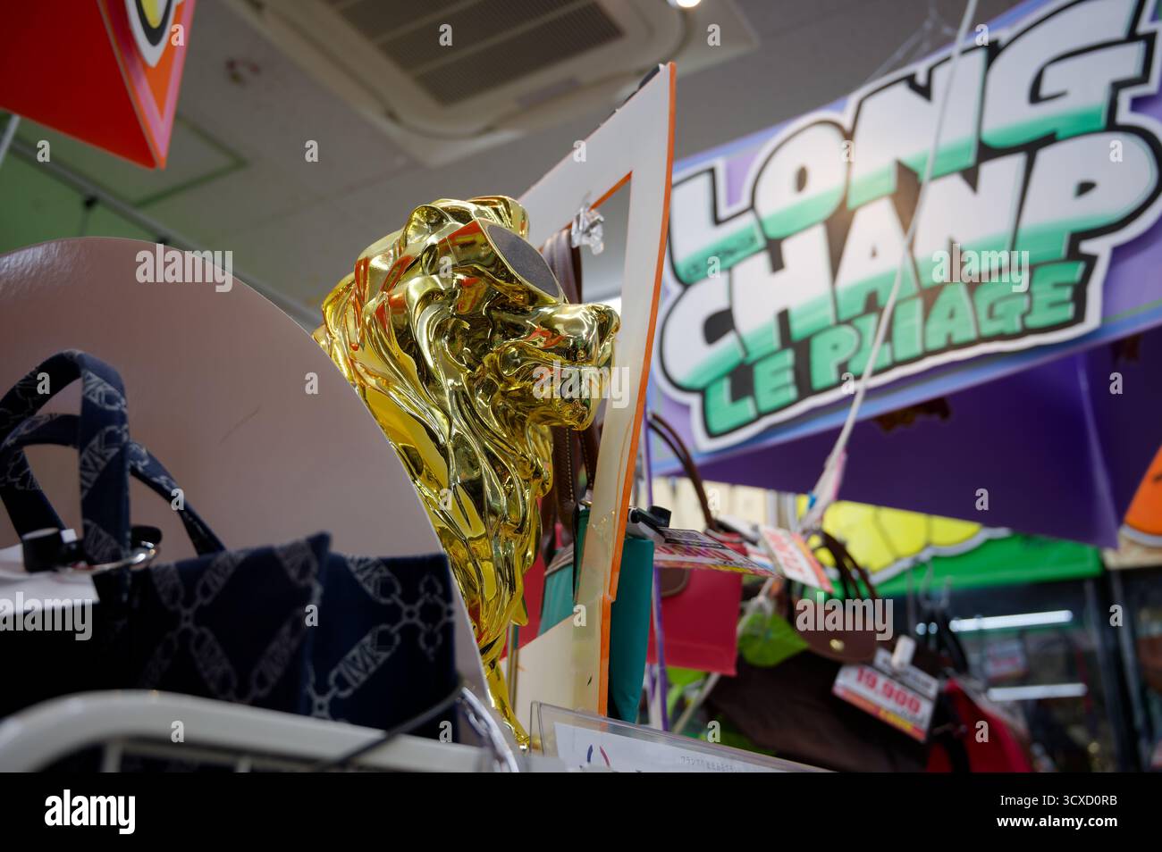 Primo piano di una scintillante scultura di leone dorato esposta tra le borse all'interno di un negozio Foto Stock