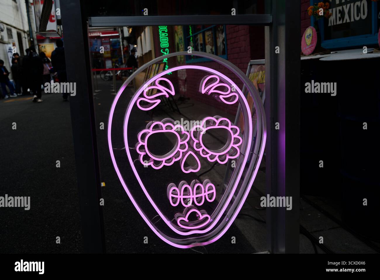 Insegna al neon a forma di teschio di zucchero che si illumina di rosa all'esterno di un ristorante messicano di Osaka Foto Stock