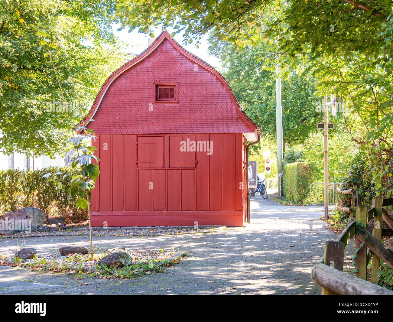 Lucerna, Svizzera - 24 settembre 2023: Un piccolo capannone di legno rosso con un tetto curvo circondato da alberi e un sentiero. Foto Stock