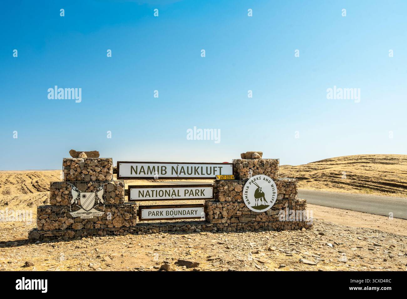 Cartello di ingresso in pietra del Parco Nazionale Namib-Naukluft in Namibia - 27 agosto 2025: Circondato da pianure desertiche e catene montuose lontane. Foto Stock