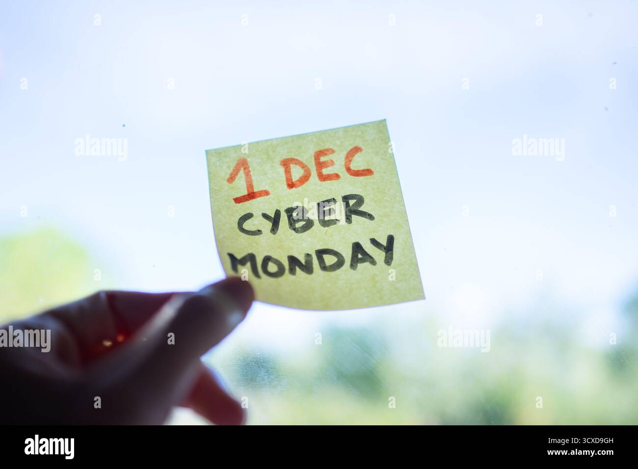 Mano con una nota adesiva gialla con il testo del lunedì cibernetico 1 dicembre su una finestra Foto Stock