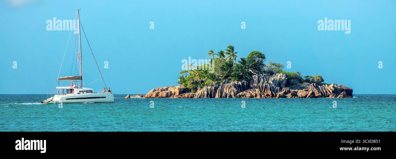 Turisti a bordo di una barca a vela sull'isola di St Pierre, isoletta rocciosa panoramica sull'isola di Praslin, testata panoramica delle Seychelles Foto Stock
